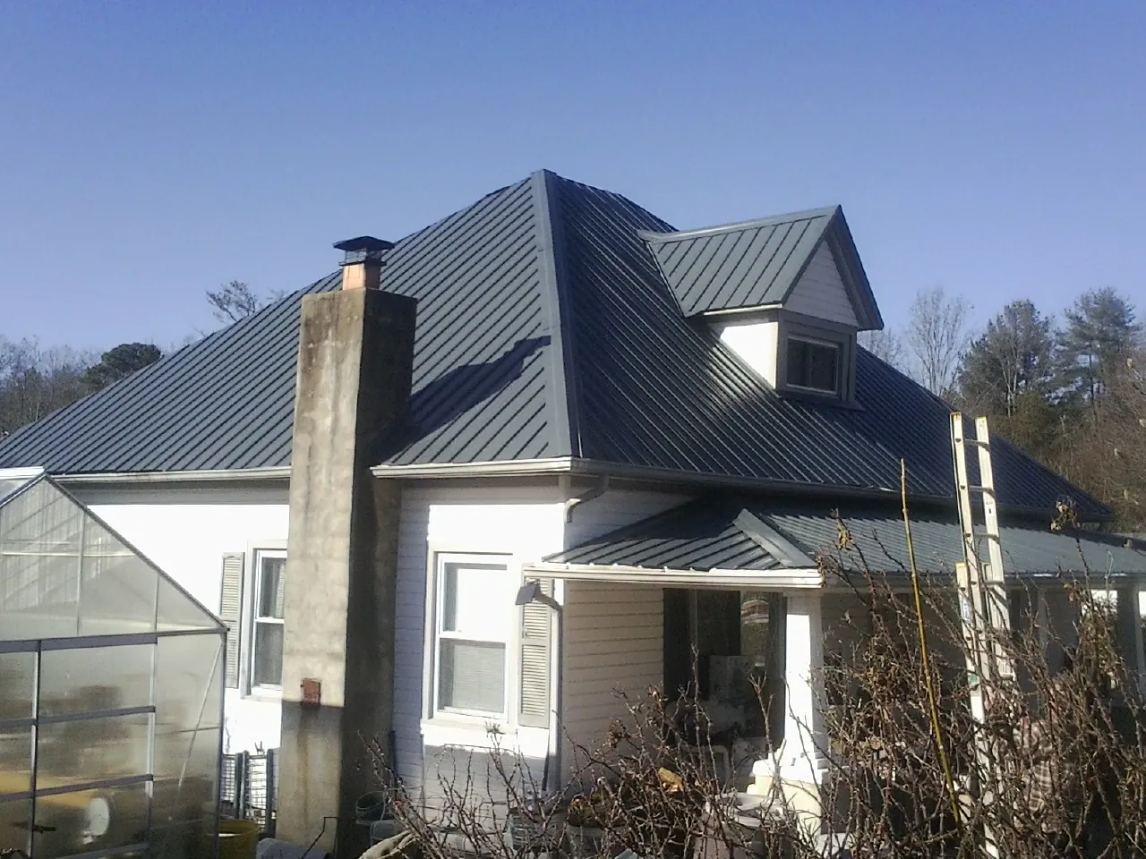 Dark blue standing seam metal roof on a white farmhouse with dormer — Slate & Tile Roof Repair by Roofing Brothers in Nephi