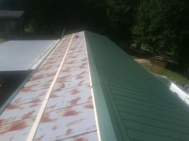 Old rusted panels beside newly installed green metal roofing — Wind Damage Roof Repair by Roofing Brothers in Nephi