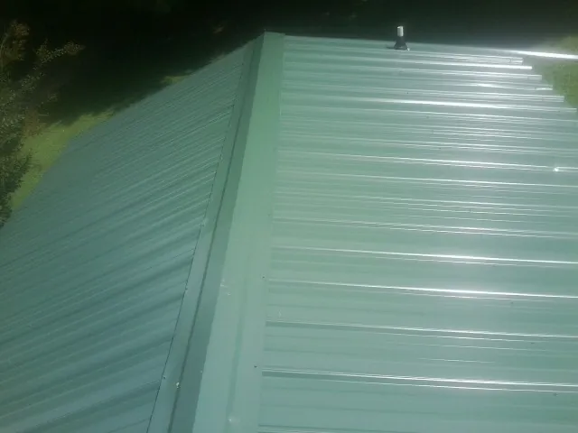 New green metal panels meeting at the ridge of a roof — Flat Roof Repair work by our crew in Nephi