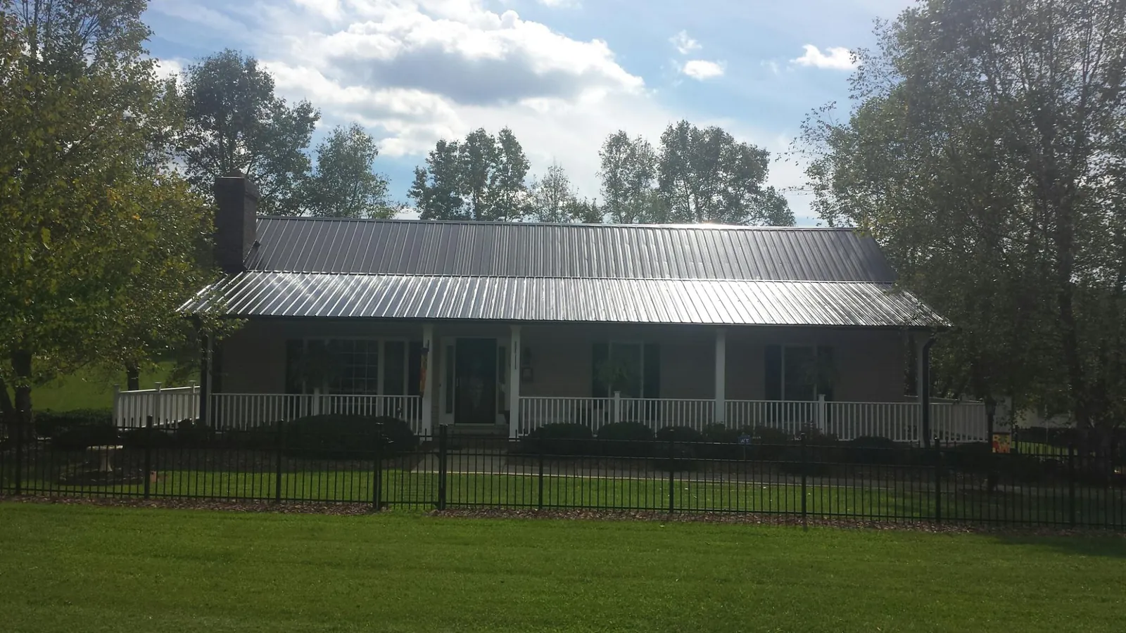Gray metal roof on a brick ranch with a full width front porch — Gutter Guard Installation work by our crew in Nephi