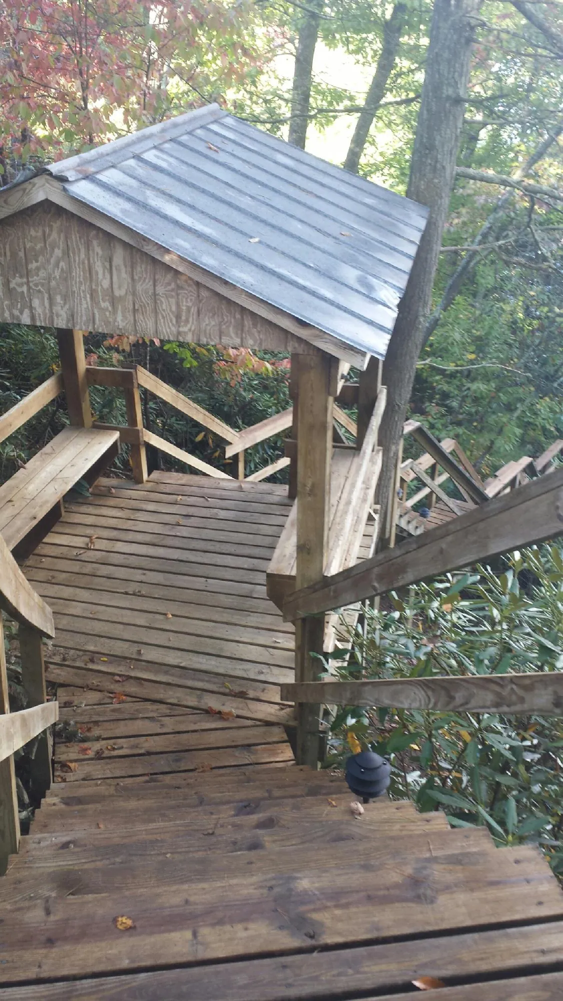 Metal roofed shelter over wooden steps on a wooded walkway — Skylight Repair & Installation work by our crew in Nephi
