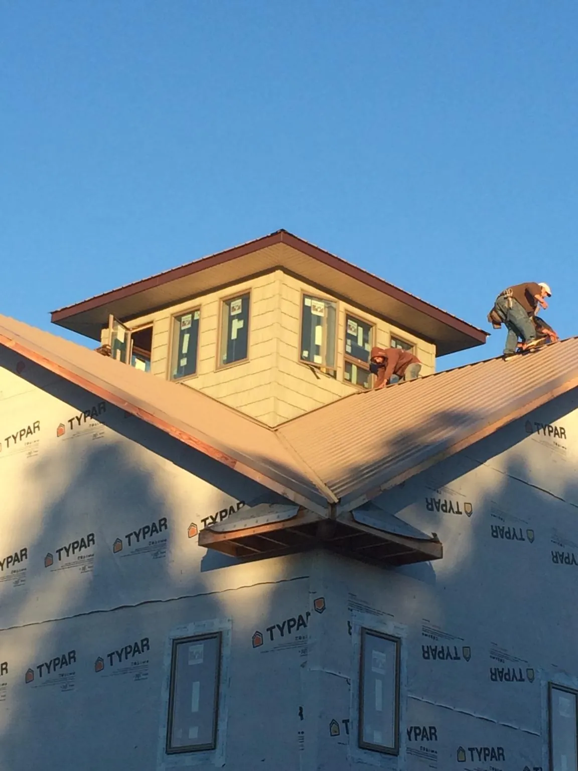 Roofers working around a rooftop cupola on a new metal roof at sunset — Roof Waterproofing in Nephi by Roofing Brothers